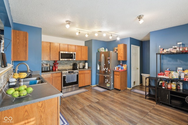 2887 Ludwig Dr, Indianapolis, IN 46239 - kitchen featuring stainless steel appliances, a sink, decorative backsplash, brown cabinetry, and wood finished floors