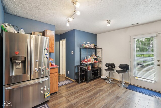 2887 Ludwig Dr, Indianapolis, IN 46239 - kitchen with stainless steel fridge with ice dispenser, rail lighting, a textured ceiling, baseboards, and brown cabinets