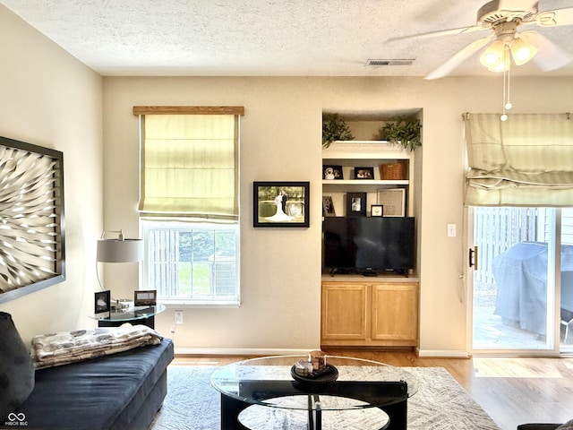 7042 Gavin Dr, Indianapolis, IN 46217 - living room featuring light wood-style flooring, healthy amount of natural light, a textured ceiling, and a ceiling fan