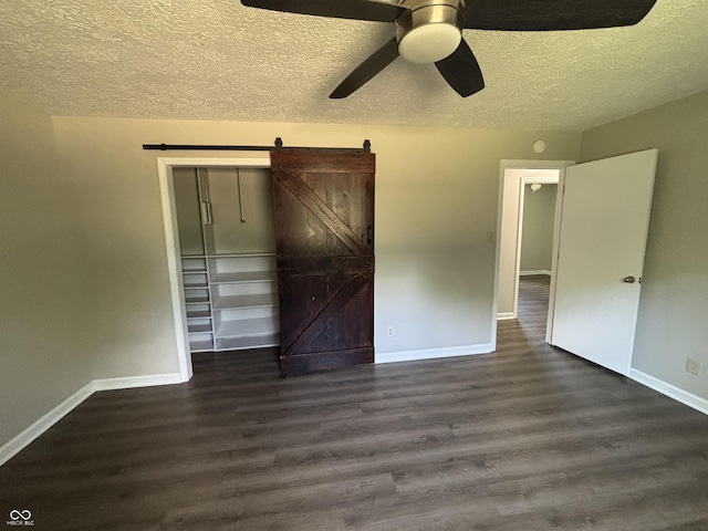4343 W Fairview Rd, Greenwood, IN 46142 - unfurnished bedroom with a textured ceiling, dark wood-style floors, a barn door, and ceiling fan