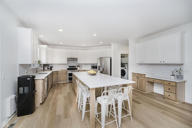 3876 Kegler Way, Carmel, IN 46074 - kitchen with appliances with stainless steel finishes, washer / dryer, a sink, a center island, and backsplash