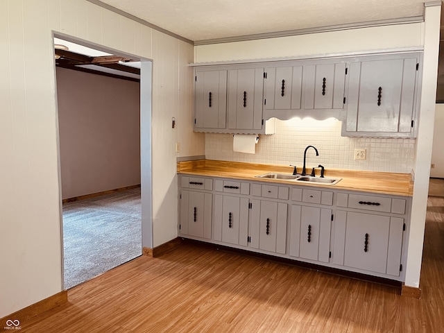 514 W 6th St, Sheridan, IN 46069 - kitchen featuring a sink, crown molding, light wood finished floors, light countertops, and decorative backsplash