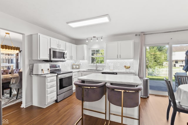 2326 Gradison Cir, Indianapolis, IN 46214 - kitchen featuring appliances with stainless steel finishes, light countertops, a kitchen breakfast bar, tasteful backsplash, and dark wood-type flooring