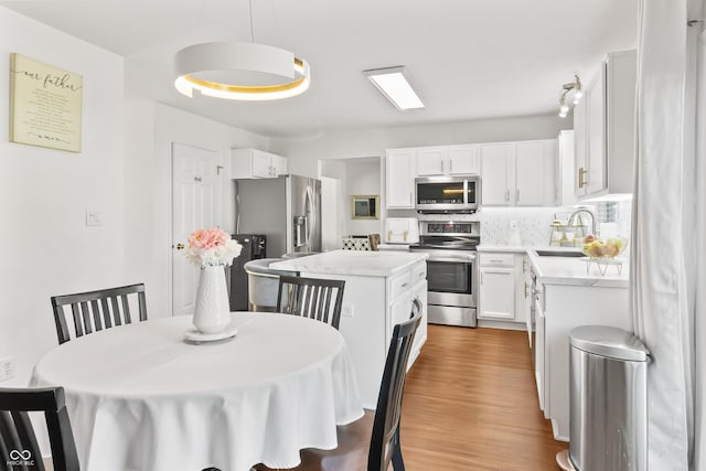 2326 Gradison Cir, Indianapolis, IN 46214 - kitchen with appliances with stainless steel finishes, a sink, light countertops, a kitchen island, and white cabinets