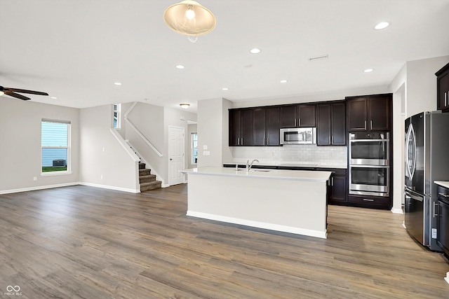 6762 Brentwood Ct, Brownsburg, IN 46112 - kitchen with stainless steel appliances, open floor plan, tasteful backsplash, ceiling fan, and wood finished floors