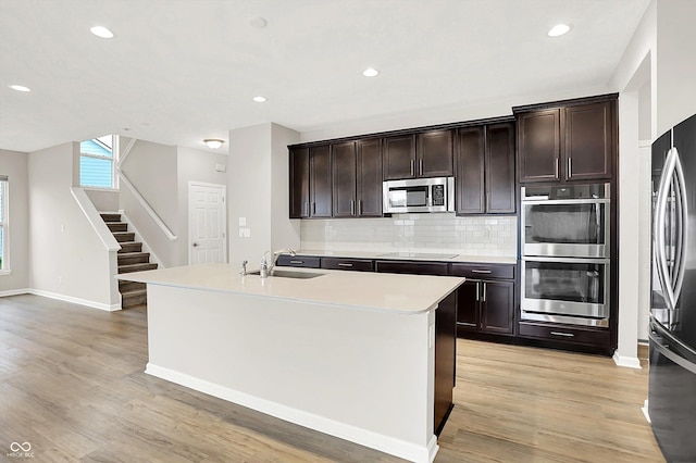 6762 Brentwood Ct, Brownsburg, IN 46112 - kitchen featuring stainless steel appliances, a sink, light wood-style flooring, backsplash, and dark brown cabinets