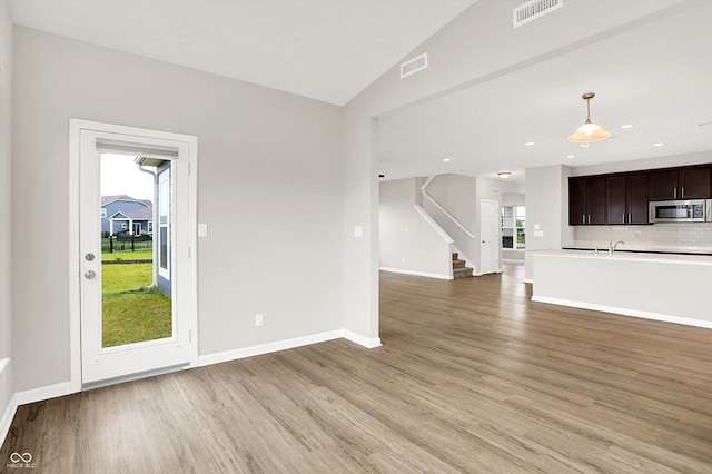 6762 Brentwood Ct, Brownsburg, IN 46112 - unfurnished living room with light wood-type flooring, baseboards, stairway, lofted ceiling, and a sink