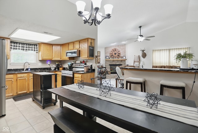 2145 W Autumn Ln, Columbus, IN 47201 - dining room featuring lofted ceiling, a fireplace, light tile patterned floors, ceiling fan, and a chandelier