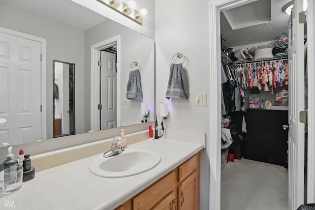2145 W Autumn Ln, Columbus, IN 47201 - bathroom with vanity, a spacious closet, and a textured ceiling