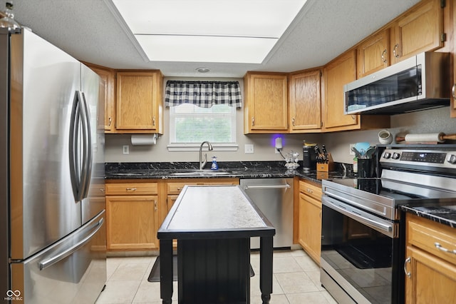 2145 W Autumn Ln, Columbus, IN 47201 - kitchen with appliances with stainless steel finishes, a sink, light tile patterned flooring, dark stone countertops, and brown cabinetry