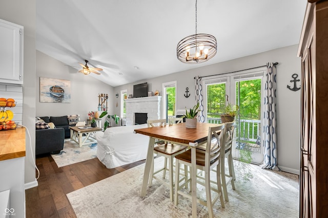 6933 Grey Wolf Dr, Hamblen Township, IN 46164 - dining area featuring a fireplace, dark wood-style floors, lofted ceiling, a ceiling fan, and a chandelier