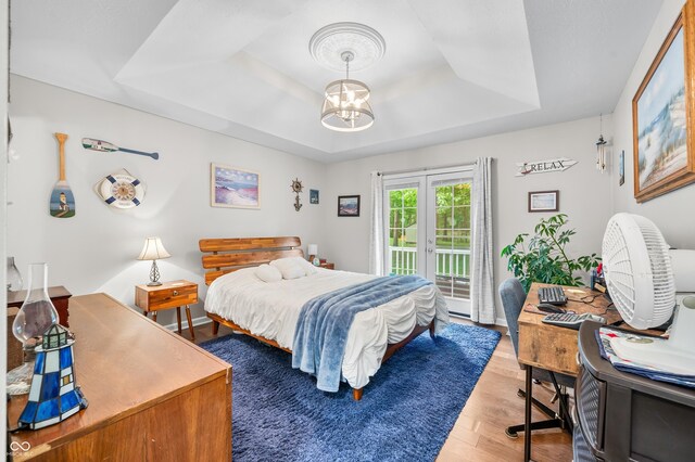 6933 Grey Wolf Dr, Hamblen Township, IN 46164 - bedroom featuring a tray ceiling, access to exterior, wood finished floors, a chandelier, and french doors