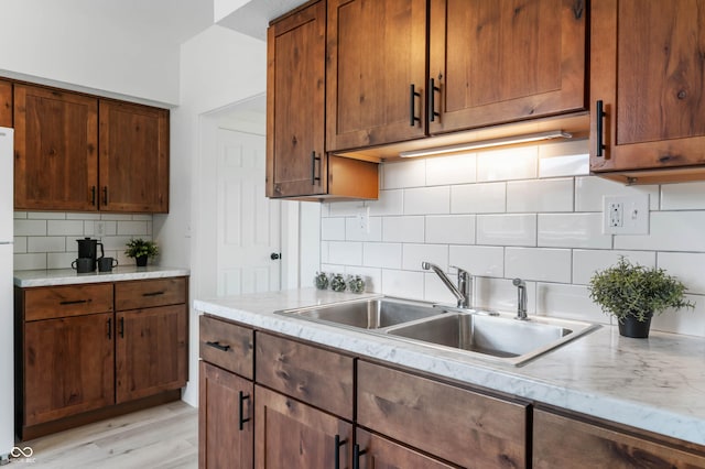 2602 State St, New Castle, IN 47362 - kitchen with a sink, backsplash, light wood finished floors, light stone counters, and brown cabinets