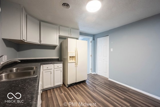5050 W Regent St, Indianapolis, IN 46241 - kitchen featuring white refrigerator with ice dispenser, a sink, dark wood-style flooring, a textured ceiling, and white cabinets