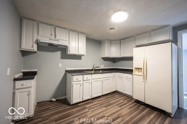 5050 W Regent St, Indianapolis, IN 46241 - kitchen featuring white fridge with ice dispenser, under cabinet range hood, a sink, dark wood-type flooring, and dark countertops