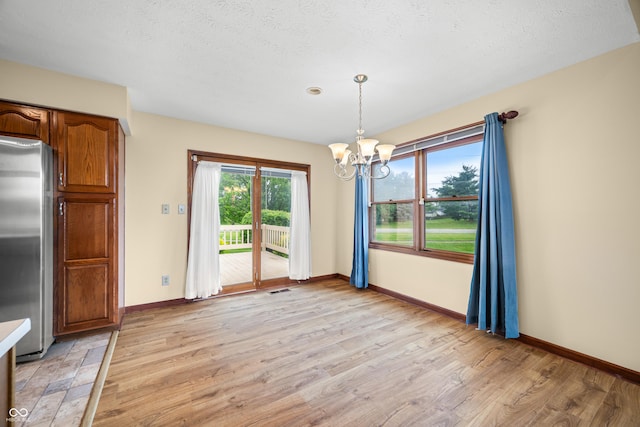 1105 Sarah Ct, Greenwood, IN 46142 - unfurnished dining area with a chandelier, baseboards, light wood-type flooring, and a textured ceiling