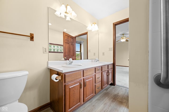 1105 Sarah Ct, Greenwood, IN 46142 - bathroom with wood finished floors, toilet, double vanity, ceiling fan, and baseboards