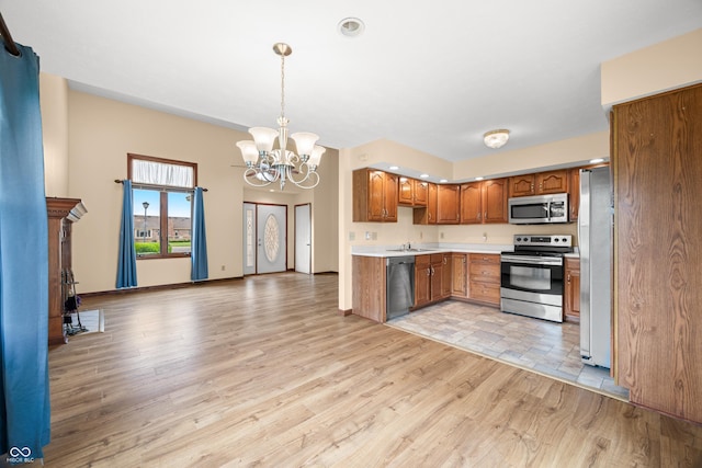 1105 Sarah Ct, Greenwood, IN 46142 - kitchen with appliances with stainless steel finishes, brown cabinetry, a chandelier, light wood finished floors, and a sink