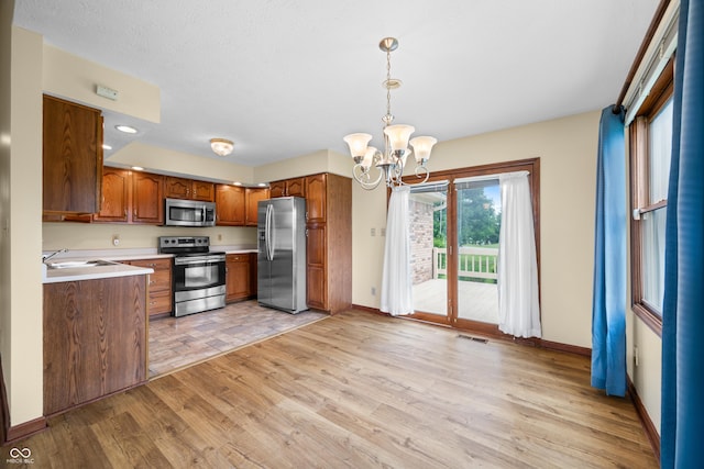 1105 Sarah Ct, Greenwood, IN 46142 - kitchen featuring stainless steel appliances, brown cabinets, a chandelier, light wood-style flooring, and baseboards