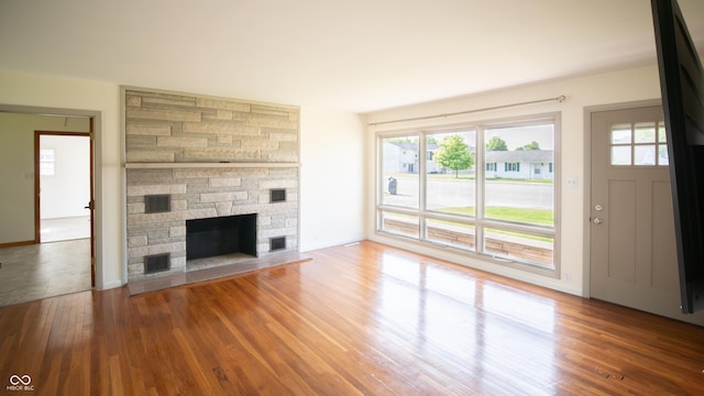 1460 W Mckay Rd, Shelbyville, IN 46176 - unfurnished living room featuring wood finished floors, plenty of natural light, and a stone fireplace