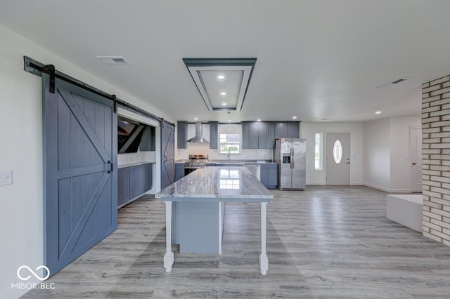 32 Downing Dr, Trafalgar, IN 46181 - kitchen featuring appliances with stainless steel finishes, wall chimney exhaust hood, a barn door, a kitchen island, and recessed lighting