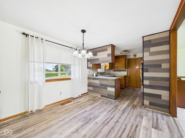 4733 E 100 S, Anderson, IN 46017 - kitchen with a peninsula, brown cabinetry, light wood-style flooring, light countertops, and a chandelier