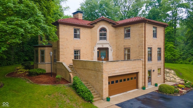 100 Leland St, New Castle, IN 47362 - mediterranean / spanish-style home featuring an attached garage, a chimney, stairs, a tile roof, and driveway