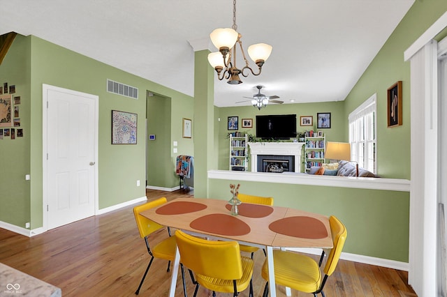 8030 Parcrest Ct, Indianapolis, IN 46259 - dining room with a ceiling fan, a fireplace, a chandelier, and wood finished floors