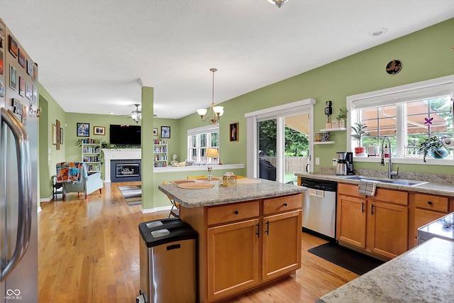 8030 Parcrest Ct, Indianapolis, IN 46259 - kitchen with stainless steel appliances, a fireplace, light wood-type flooring, open floor plan, and a ceiling fan