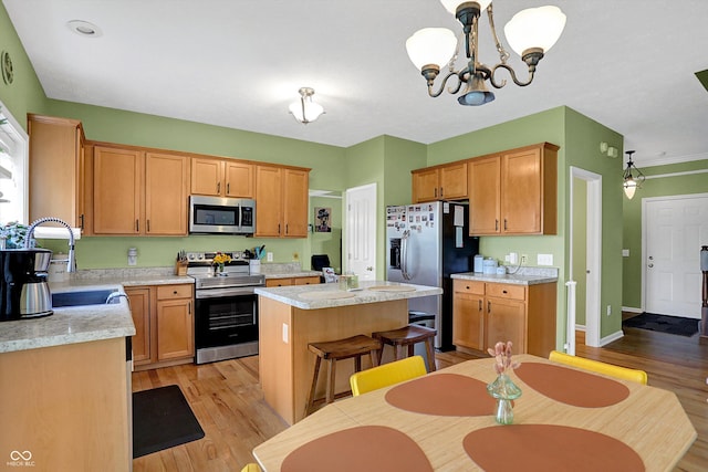 8030 Parcrest Ct, Indianapolis, IN 46259 - kitchen with stainless steel appliances, light countertops, light wood finished floors, a kitchen island, and a chandelier