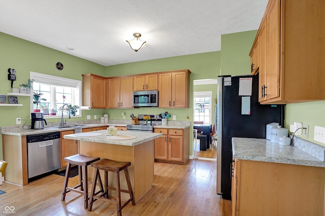 8030 Parcrest Ct, Indianapolis, IN 46259 - kitchen featuring appliances with stainless steel finishes, light wood-style flooring, light countertops, a kitchen island, and a kitchen bar
