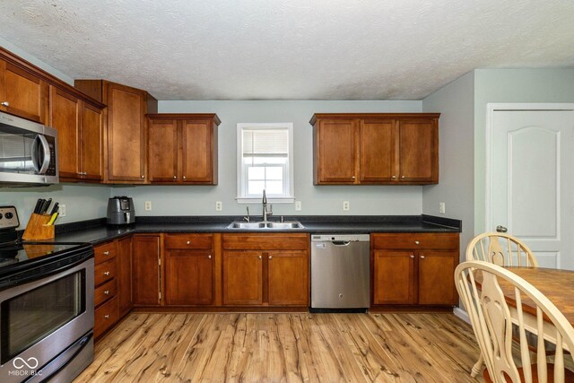 29 Northview Dr, Danville, IN 46122 - kitchen with stainless steel appliances, a sink, light wood finished floors, brown cabinetry, and dark countertops