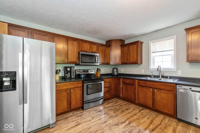 29 Northview Dr, Danville, IN 46122 - kitchen featuring stainless steel appliances, a sink, light wood-style floors, brown cabinetry, and a textured ceiling