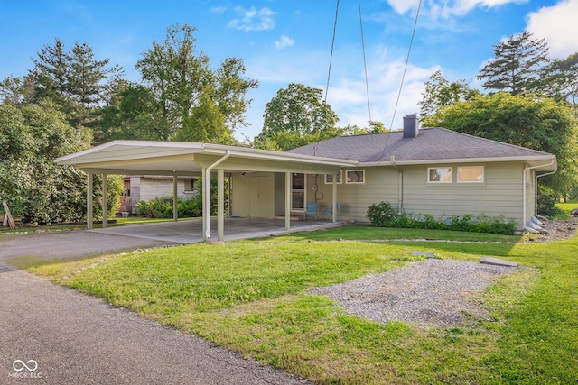 2233 Washington St, Columbus, IN 47201 - view of front of house featuring a carport, a front lawn, a chimney, and asphalt driveway