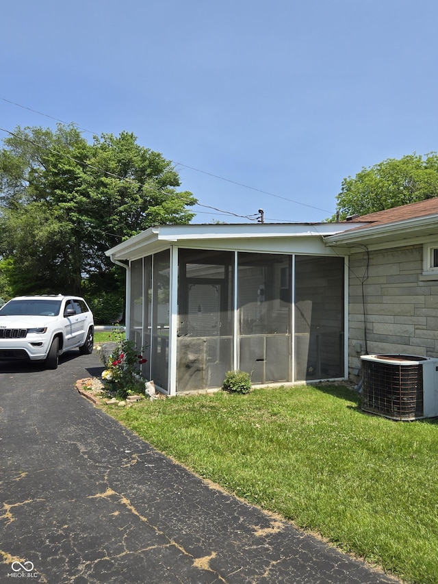 104 Meadow Ln, North Vernon, IN 47265 - view of side of home featuring central AC unit, a sunroom, and a lawn