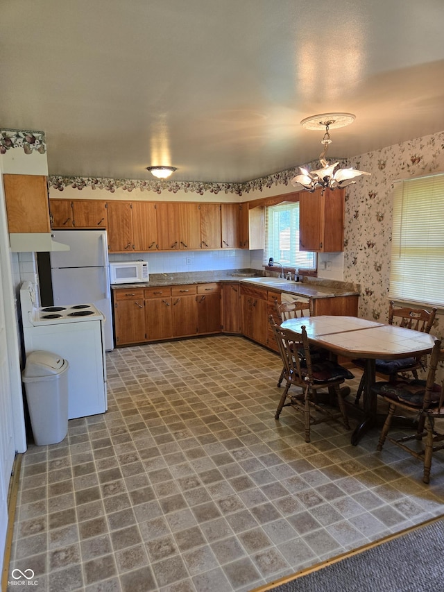 104 Meadow Ln, North Vernon, IN 47265 - kitchen with white appliances, a chandelier, wallpapered walls, brown cabinetry, and a sink