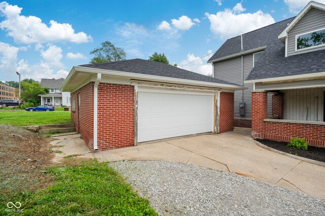 110 E Mcdonald St, Brazil, IN 47834 - view of side of property featuring brick siding, a garage, roof with shingles, an outbuilding, and driveway