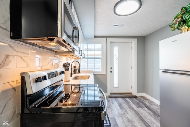 1631 Columbia Ave, Indianapolis, IN 46202 - kitchen featuring appliances with stainless steel finishes, wood finished floors, a sink, baseboards, and tasteful backsplash