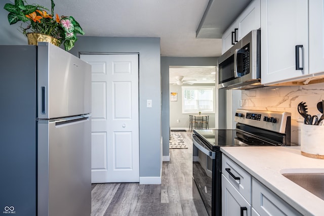1631 Columbia Ave, Indianapolis, IN 46202 - kitchen featuring appliances with stainless steel finishes, wood finished floors, tasteful backsplash, white cabinets, and baseboards