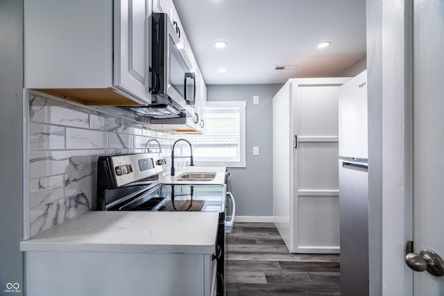 1631 Columbia Ave, Indianapolis, IN 46202 - kitchen featuring a sink, appliances with stainless steel finishes, dark wood-style flooring, tasteful backsplash, and light stone counters