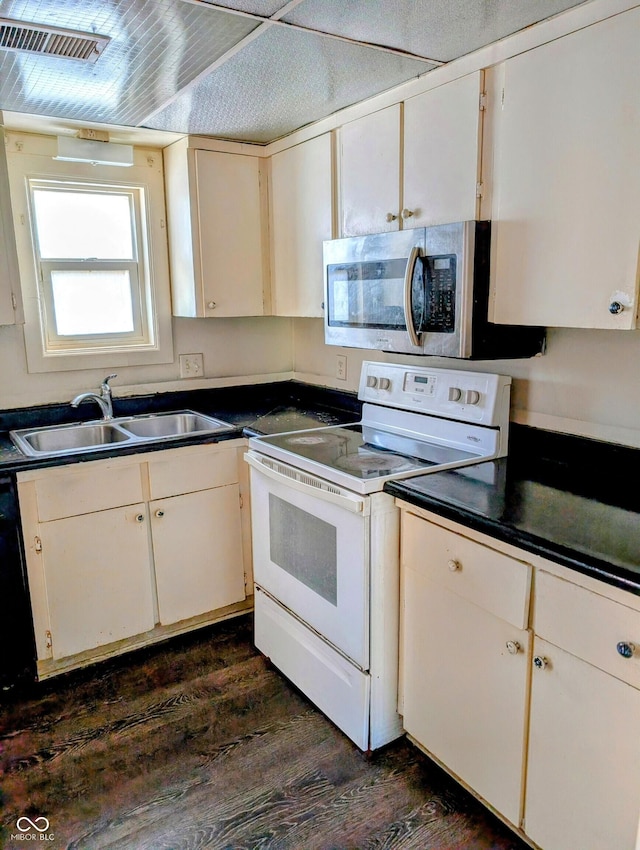 6322 Commons Dr, Indianapolis, IN 46254 - kitchen featuring white electric range oven, stainless steel microwave, a sink, dark wood-style floors, and dark countertops