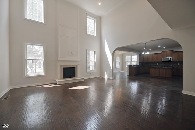 15201 Slateford Rd, Noblesville, IN 46062 - unfurnished living room featuring arched walkways, plenty of natural light, dark wood finished floors, a high ceiling, and baseboards