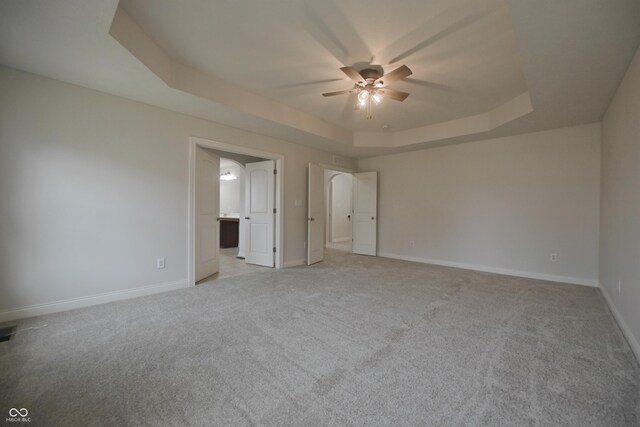15201 Slateford Rd, Noblesville, IN 46062 - unfurnished bedroom featuring a tray ceiling, light colored carpet, baseboards, ensuite bathroom, and a ceiling fan