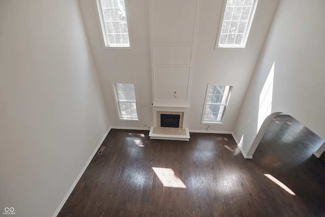 15201 Slateford Rd, Noblesville, IN 46062 - unfurnished living room featuring healthy amount of natural light, baseboards, dark wood finished floors, a tiled fireplace, and a towering ceiling