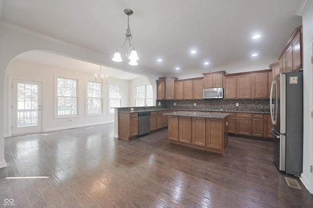 15201 Slateford Rd, Noblesville, IN 46062 - kitchen with stainless steel appliances, arched walkways, a chandelier, brown cabinetry, and ornamental molding