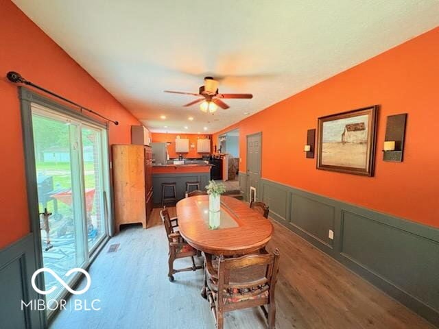 8990 N 850 W, Fairland, IN 46126 - dining room featuring light wood finished floors, ceiling fan, a wainscoted wall, and a decorative wall