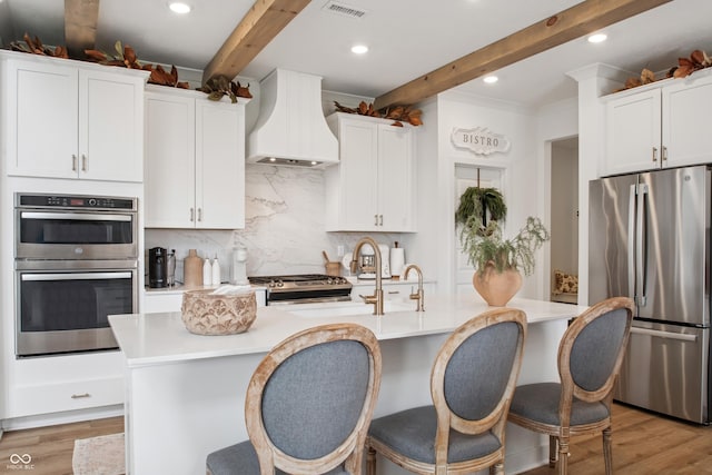 19652 Shadow Trace Path, Westfield, IN 46074 - kitchen with stainless steel appliances, custom exhaust hood, beamed ceiling, decorative backsplash, and light wood-type flooring