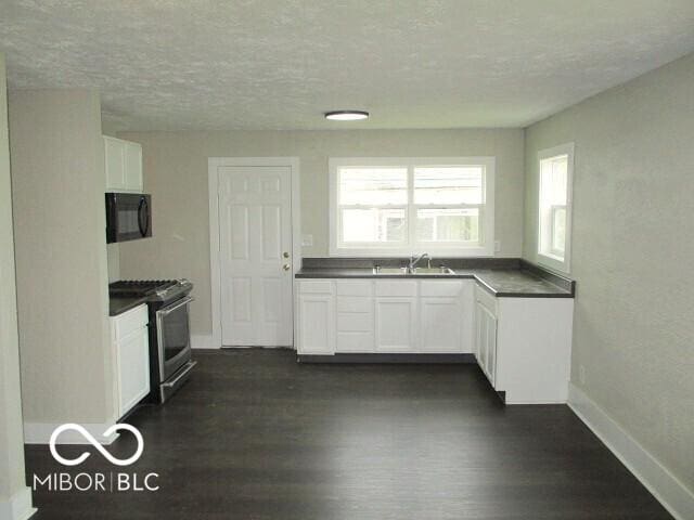 620 S 2nd St, Noblesville, IN 46060 - kitchen featuring gas stove, black microwave, dark wood-type flooring, dark countertops, and baseboards