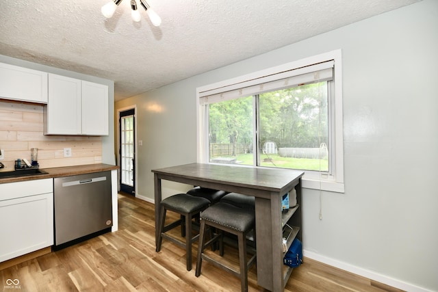 1445 Biloxi Ln, Beech Grove, IN 46107 - kitchen with stainless steel dishwasher, light wood-style flooring, white cabinetry, butcher block countertops, and a textured ceiling