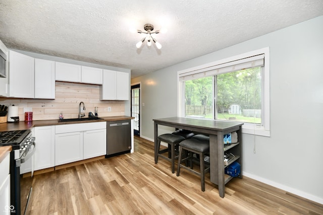 1445 Biloxi Ln, Beech Grove, IN 46107 - kitchen with stainless steel appliances, butcher block countertops, a textured ceiling, light wood finished floors, and white cabinets